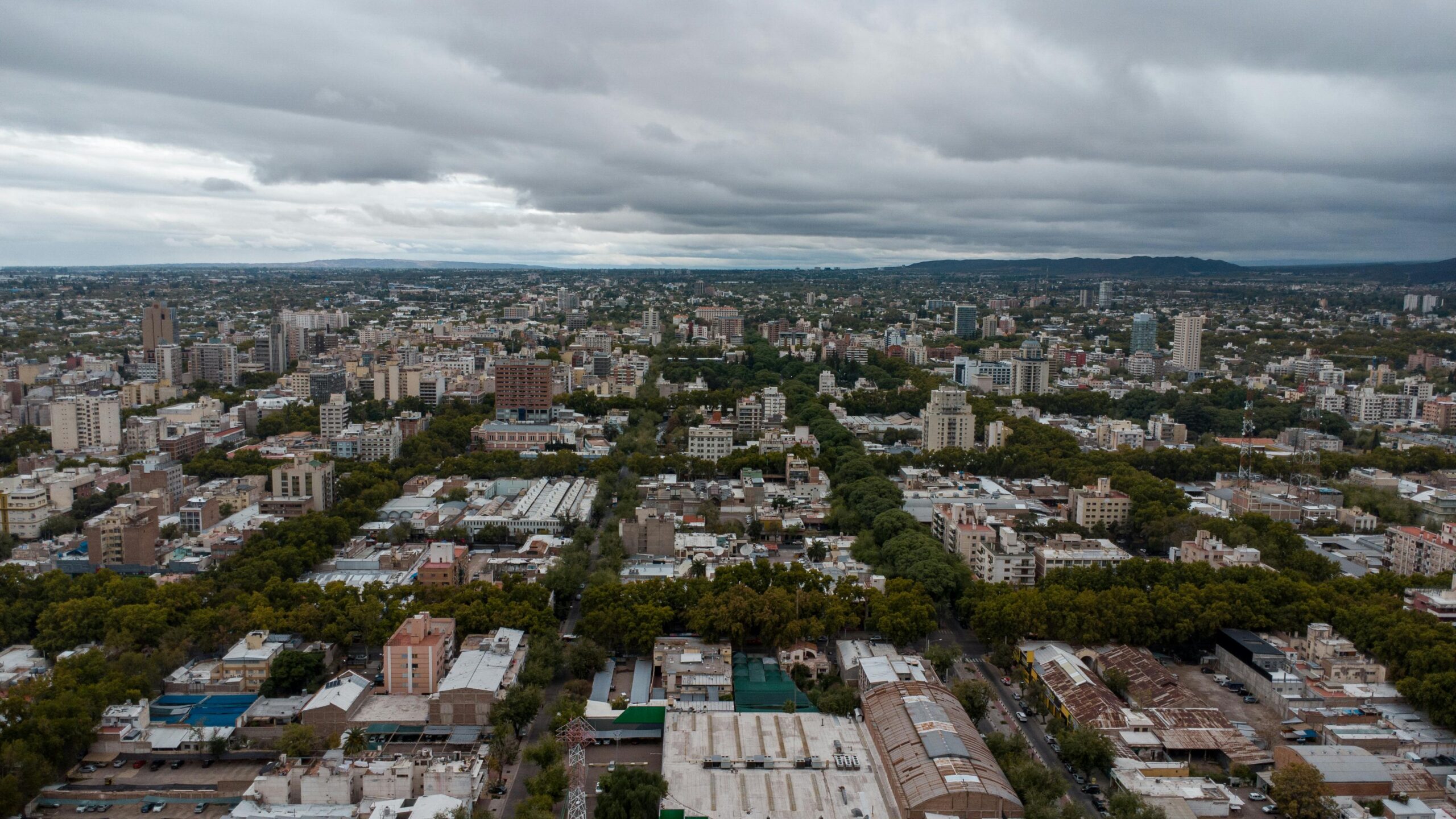 Discover a stunning aerial view of Mendoza City, showcasing urban landscapes amidst lush greenery.