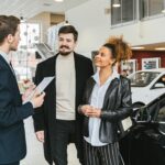 Couple discussing car purchase with salesman at indoor dealership, engaging conversation.