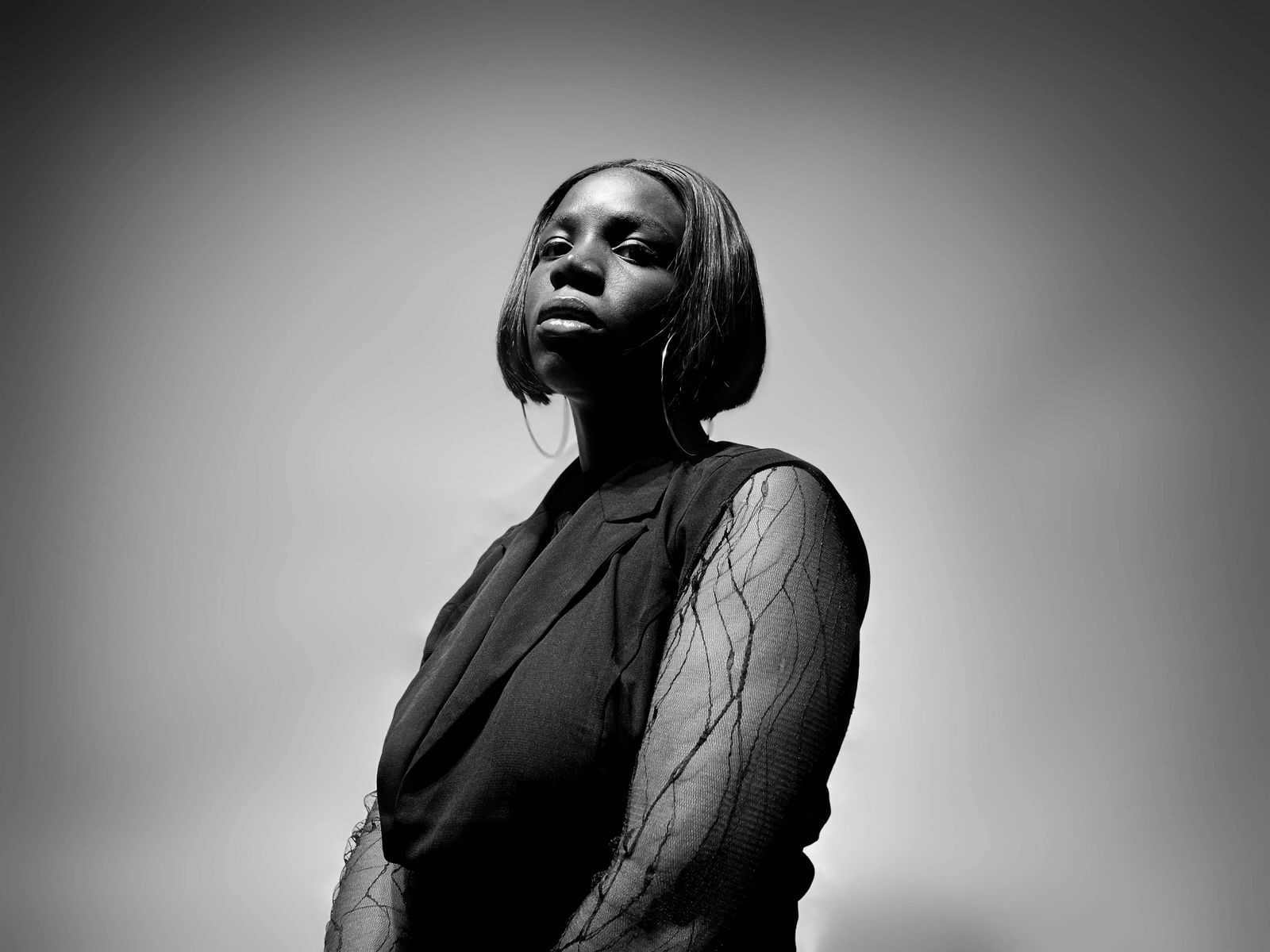 A striking black and white portrait of a woman in elegant attire, captured in a studio setting.
